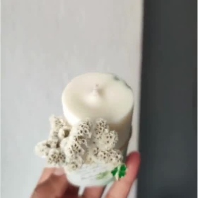 Vela decorativa branca e verde com flores secas e cartão pendurado