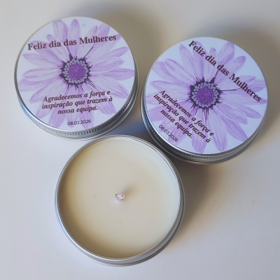 Três velas em recipiente metálico com tampa decorada em rosa e texto em português.