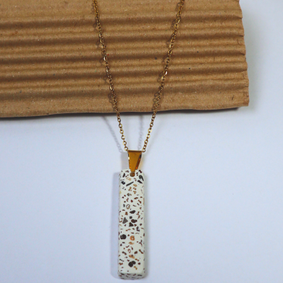 Colar com pendente retangular branco com manchas castanhas e pretas e corrente dourada