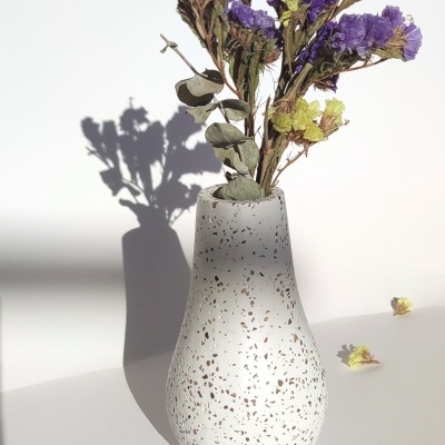 Vaso cerâmico branco com manchas marrons e flores secas roxas e amarelas