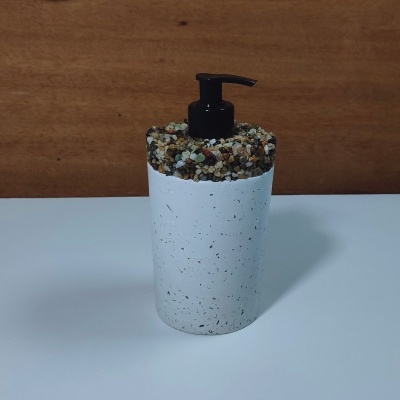 Frasco dosificador branco com textura de pequenas pedras no topo e bomba preta
