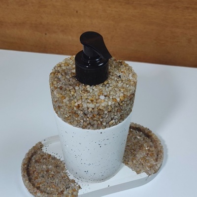 frasco branco com tampa preta decorado com seixos em base com seixos