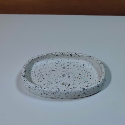 Saboneteira oval branca com manchas pretas e castanhas e três orifícios no centro