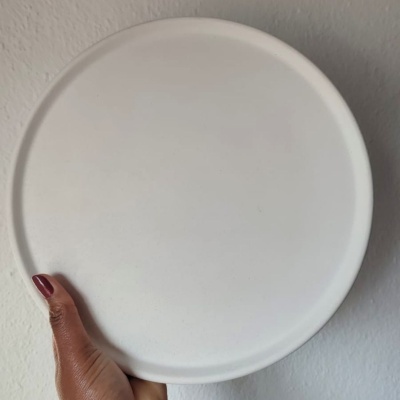 Prato redondo branco cerâmico segurado por mão