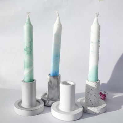 Três velas marmoreadas com suportes de vela em mármore e pedra sobre fundo branco