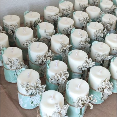 Velas decorativas cilíndricas com flores secas e etiquetas em cordão.