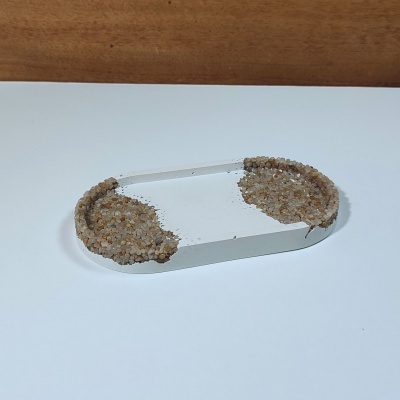 Prato oval decorativo branco com bordas cobertas por grãos de areia