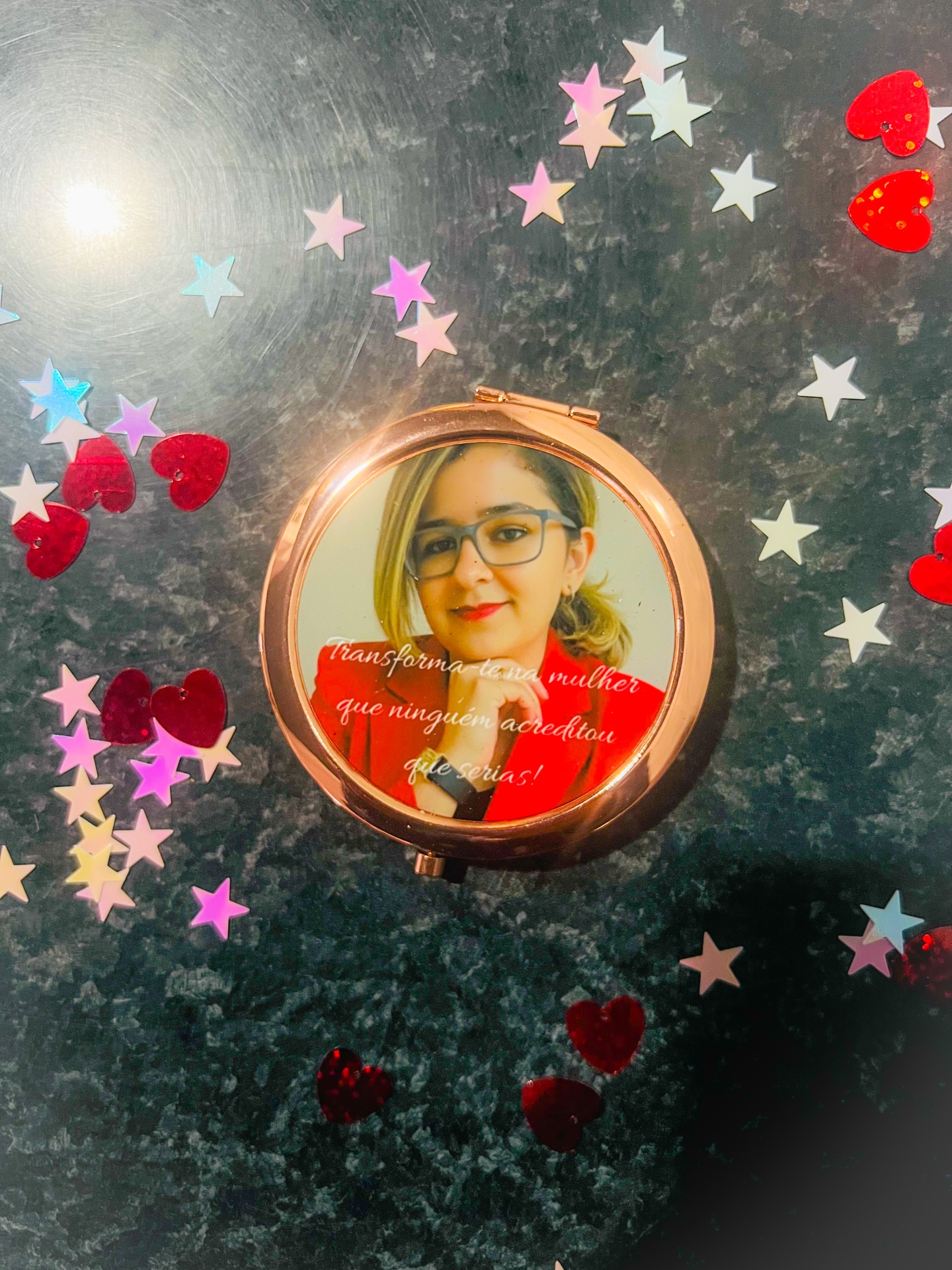 Espelho de bolso com imagem e texto decorativo rodeado de confetis coloridos