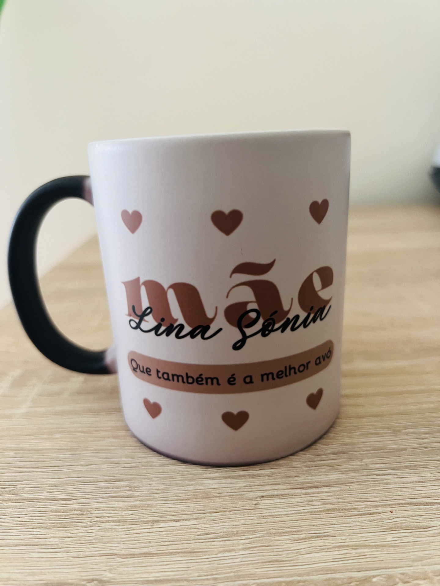 Caneca branca com corações castanhos e texto em português sobre mãe e avó