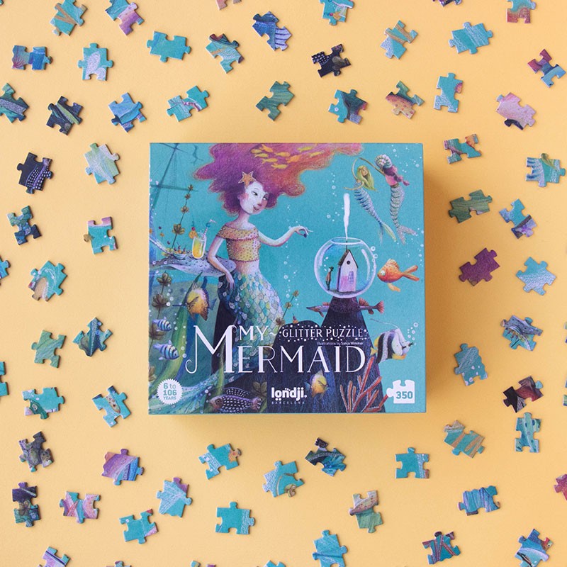 Quebra-cabeças MY MERMAID GLITTER PUZZLE com imagem de sereia e peixes, peças espalhadas em fundo amarelo.
