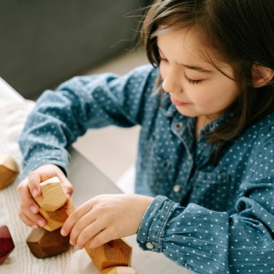 Criança a brincar com blocos de madeira coloridos numa mesa