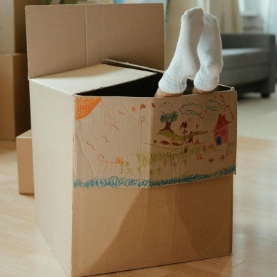 Caixa de cartão decorada com desenhos coloridos e pés de criança com meias brancas para cima