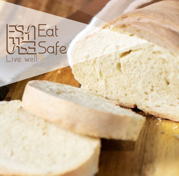 Pão branco fatiado sobre superfície de madeira com texto 'Eat Safe Live well'.