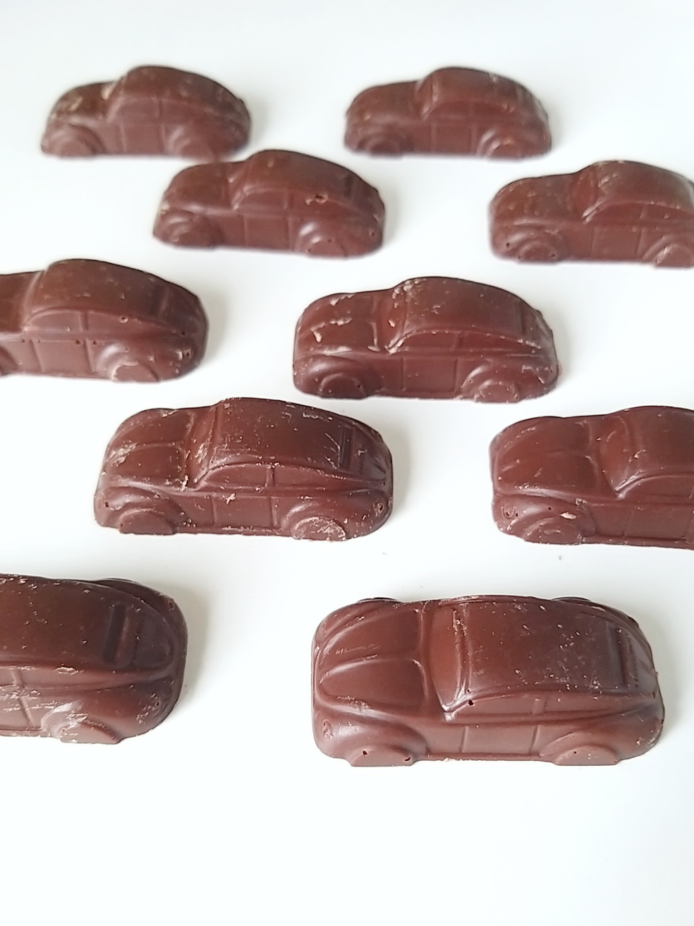 Carrinhos de chocolate 80g #Dammenberg sem glúten Dez bombons de chocolate em forma de carros clássicos castanhos escuros em fundo branco