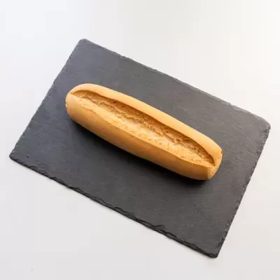 Pão baguete dourado em placa de ardósia preta