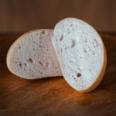 Pão branco cortado em duas metades sobre madeira