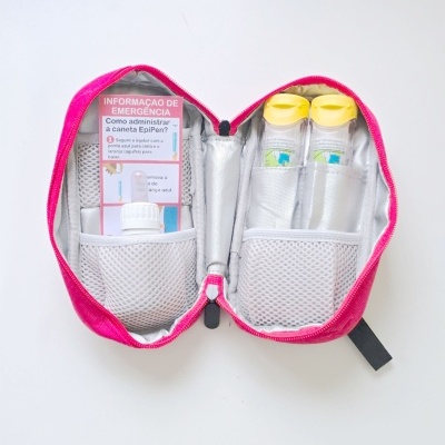 Bolsa médica rosa aberta com recipientes e instruções de emergência para EpiPen