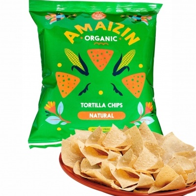 Sacos verdes de tortilha chips Amaizin Organic Natural com tortilhas de milho em prato