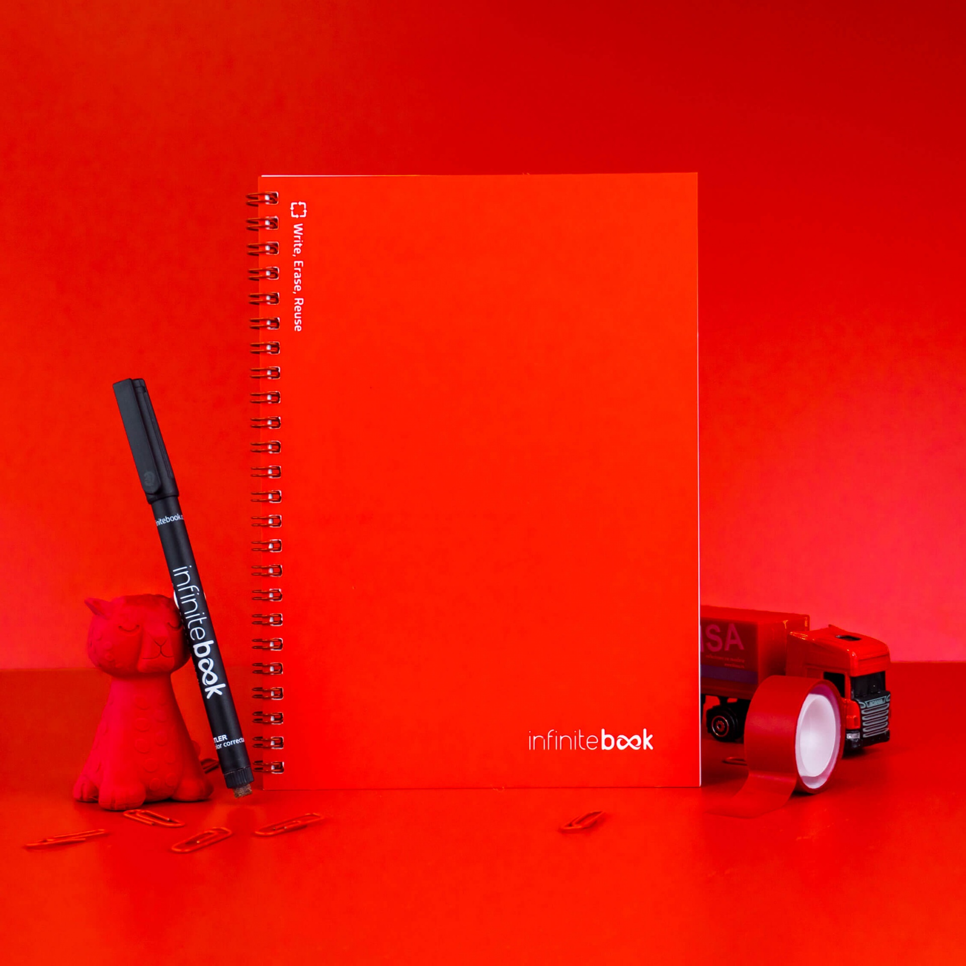 Caderno reutilizável Infinitebook - A5 Vermelho Caderno vermelho espiral com caneta preta e brinquedos sobre fundo vermelho