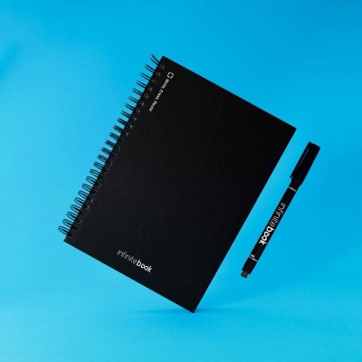 Caderno preto com espiral e caneta preta sobre fundo azul