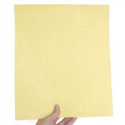 Pano amarelo quadrado com padrão texturizado, segurado por uma mão