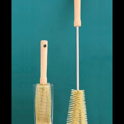 Duas escovas de limpeza com cabos de madeira e cerdas claras em fundo verde