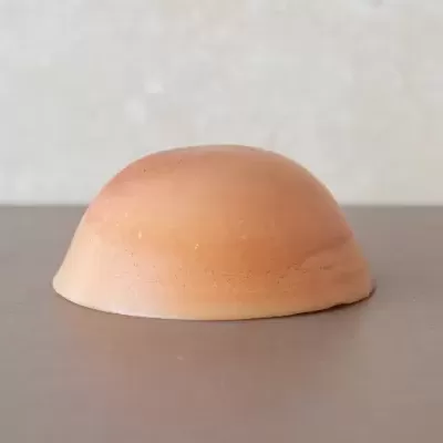 Objeto cerâmico castanho claro em forma de semiesfera sobre superfície cinzenta