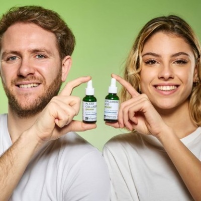 Dois adultos segurando frascos pequenos de vidro verde com conta-gotas