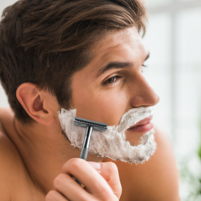 Homem a barbear-se com espuma branca e navalha preta