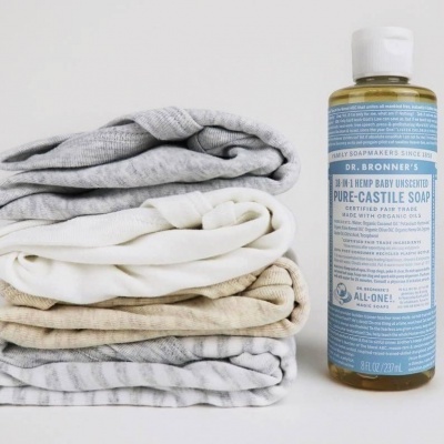 Garrafa de sabão Dr. Bronner's e toalhas dobradas em tons neutros