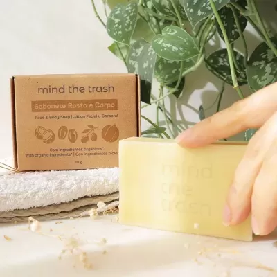 Sabonete amarelo claro com embalagem em cartão castanho e toalhas