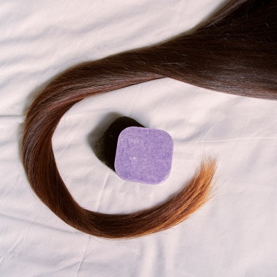 Bloco sólido roxo e cabelo castanho com pontas loiras sobre tecido branco