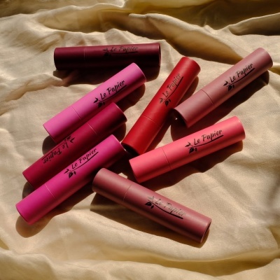 Oito batons Le Papier em várias cores sobre tecido amarelo claro