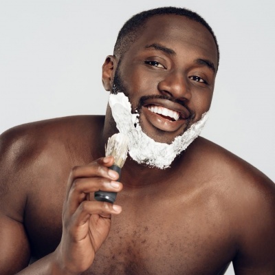 Homem a fazer a barba com pincel e espuma branca