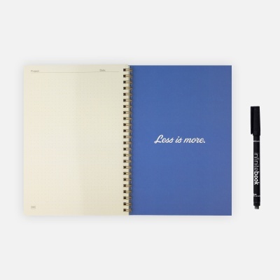 Caderno espiral azul com frase 'Less is more.' e caneta preta FINEBOOK ao lado