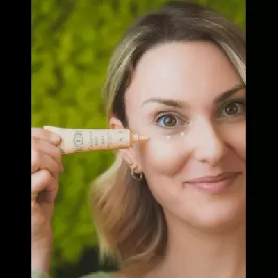 Mulher aplica creme em tubo bege claro com texto visível