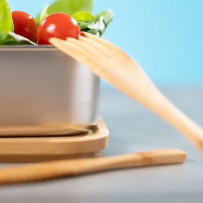 Saladeira metálica com vegetais e utensílios de cozinha em madeira