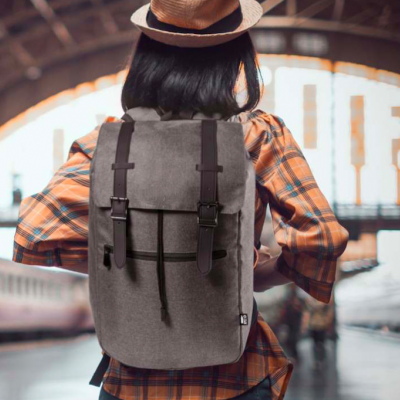 Mochila cinzenta com tiras em couro castanho numa estação de comboios