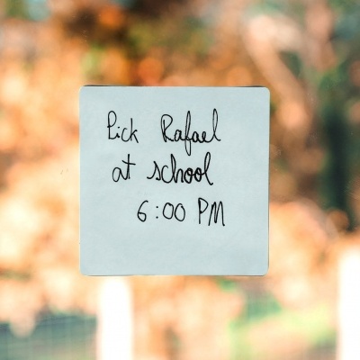 Nota adesiva azul com mensagem manuscrita a preto numa superfície de vidro