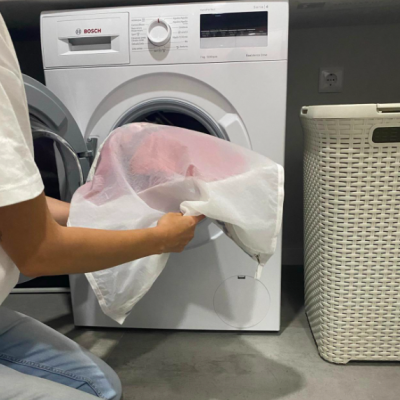 Máquina de lavar branca BOSCH Série 4 com pessoa a usar saco de lavagem e cesto de roupa bege