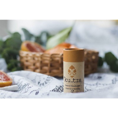 Desodorizante natural ku.tis Grapefruit & Mandarin sobre tecido branco e azul com fatia de toranja e cesta de vime ao fundo