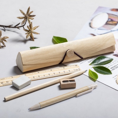 Estojo de lápis em madeira com material de escrita e folhas verdes num fundo cinza