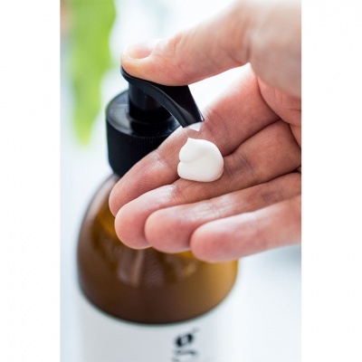 Frasco de vidro com dispensador a liberar creme para a mão