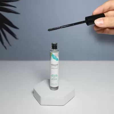 Frasco de rímel transparente com aplicador e fundo azul