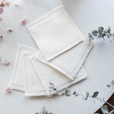 Discos de algodão reutilizáveis brancos junto com flores secas sobre mesa clara