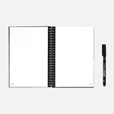 Caderno espiral aberto com páginas brancas e marcador preto ao lado