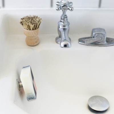 Pia branca com torneiras cromadas e escova de barbear de madeira