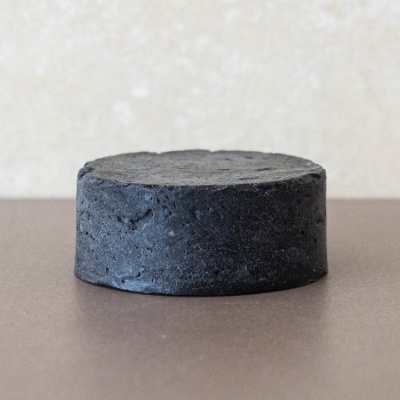 Barra sólida preta com textura porosa sobre superfície castanha lisa.