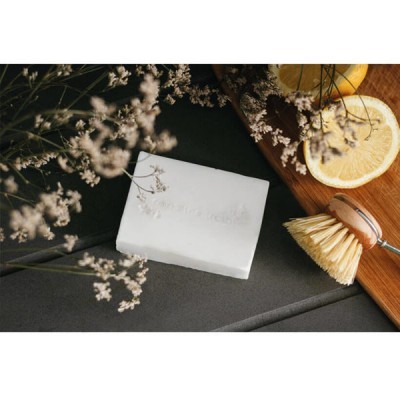 Sabão branco, escova de limpeza, fatias de limão e flores brancas sobre superfície cinza