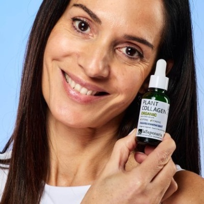 Mulher a segurar frasco verde de sérum PLANT COLLAGEN DERMADE com conta-gotas branco